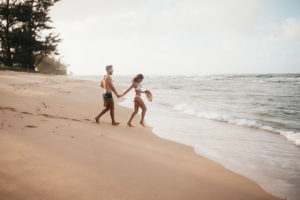Couples Photography, woman leads man across Hawaii beach to the calm waves of the ocean