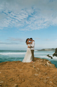 Elopment Photography, Bride and groom hold each other on rocks before the ocean